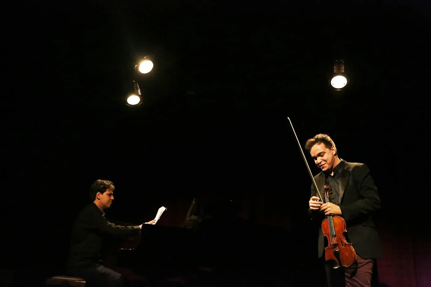 Mateus Belloni beside a pianist, on stage